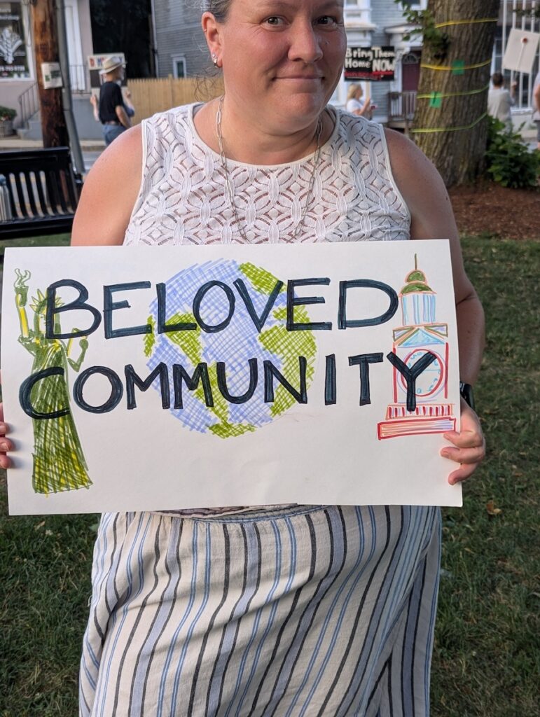 Natalie Robert holding a sign saying "Beloved Community"