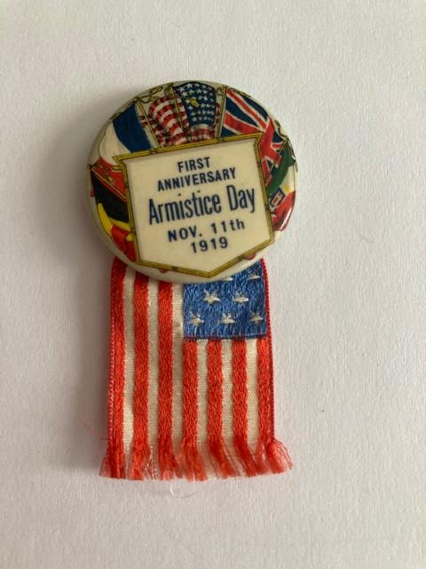 Armistice Day button from November 11, 1919, featuring an American flag ribbon and international flags