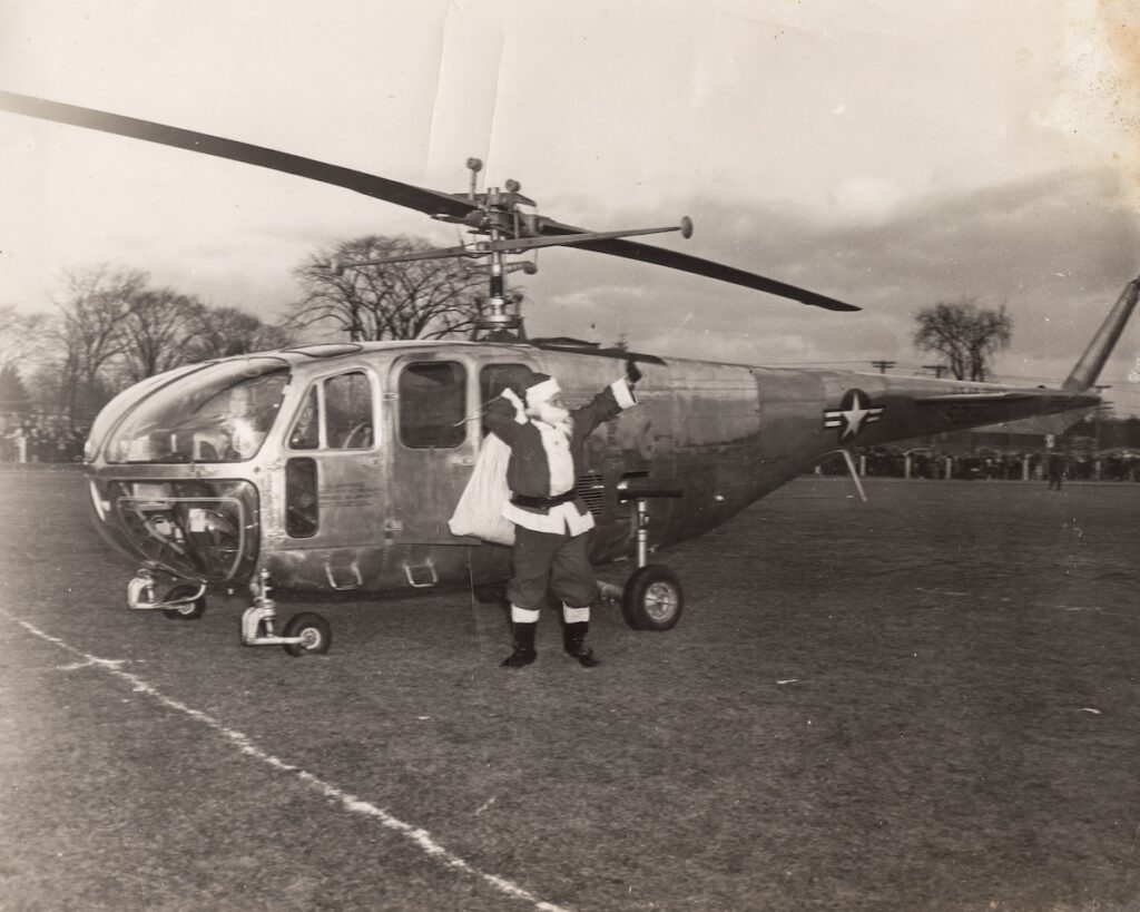 Santa standing outside a helicopter and waving at bystanders